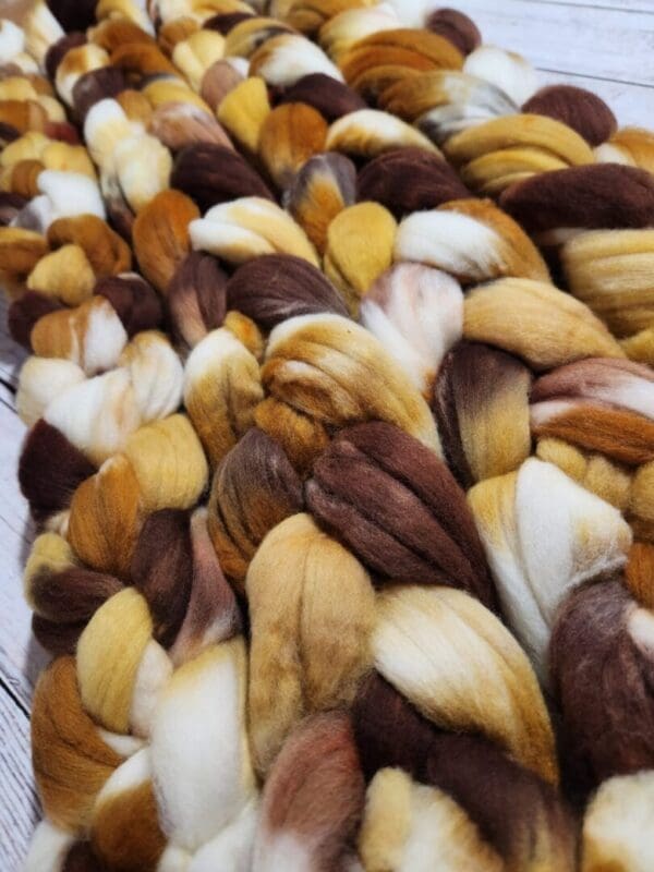 A pile of brown and white roving on a wooden table.