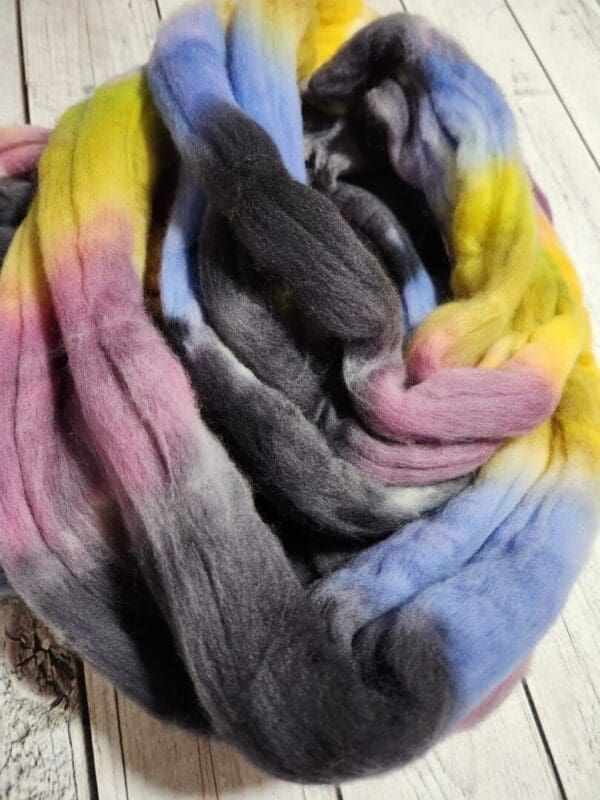 A scarf with a rainbow colored yarn on top of it.