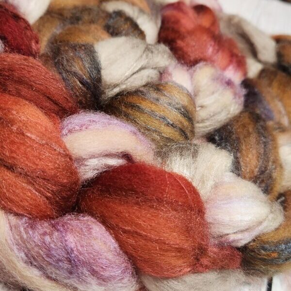 A close up of a red, orange and brown skein of roving.