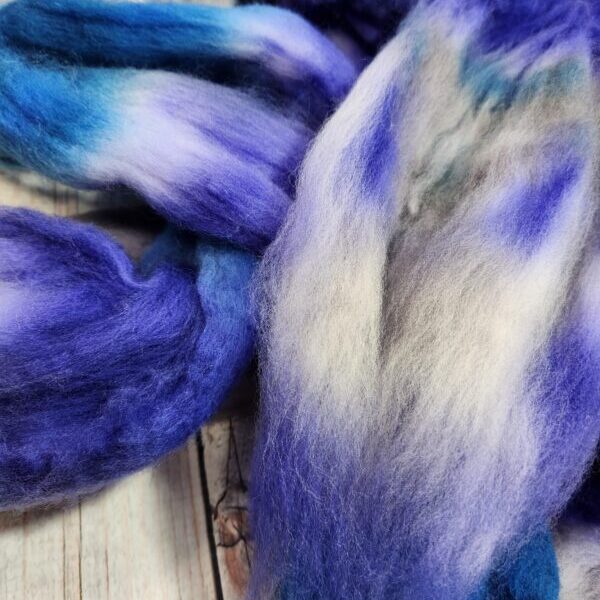 20230224_235144 A bunch of Disco Date ~ 100g Hand-Dyed Luxury Combed Top Fiber on a wooden table.