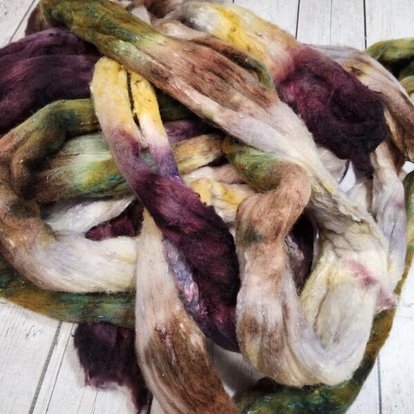 20230321_232148 A bunch of Disco Date ~ 100g Hand-Dyed Luxury Combed Top Fiber on a wooden floor.
