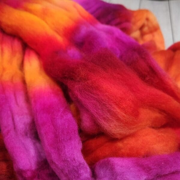 A pile of colorful fibers on top of a wooden table.