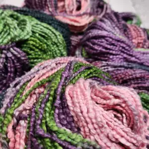 Skeins of yarn in purple and green colors.