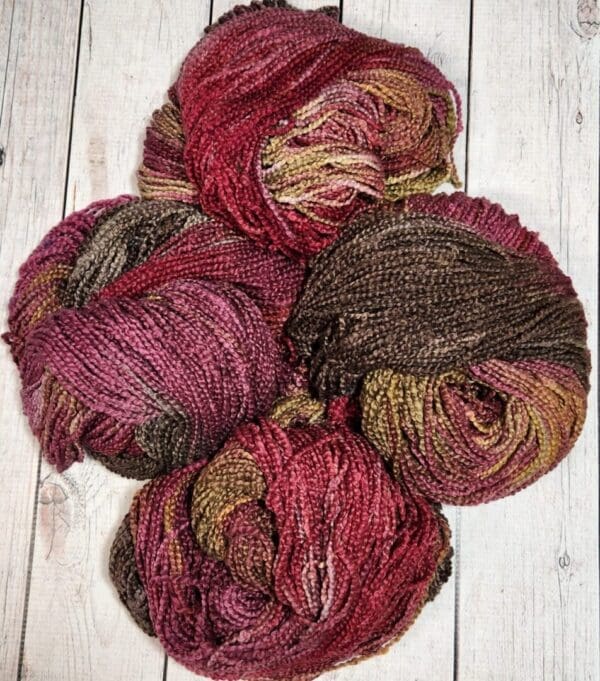 Four skeins of yarn on a wooden surface.