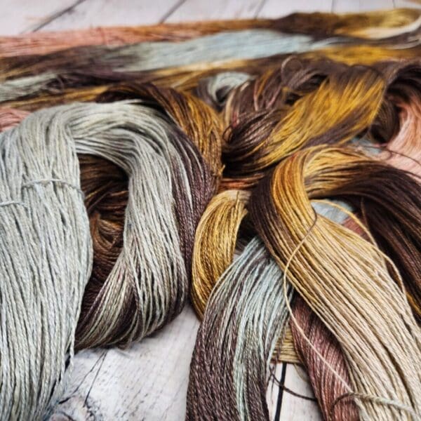 A bunch of different colored yarns on a wooden surface.