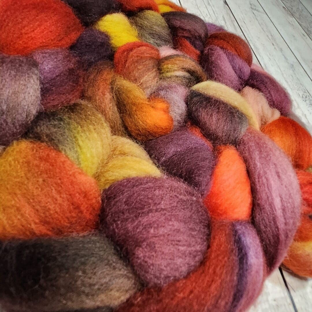 A pile of red, orange, and yellow fibers on a wooden floor.