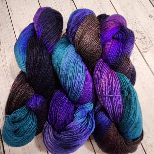 Purple, blue and black skeins on a wooden table.