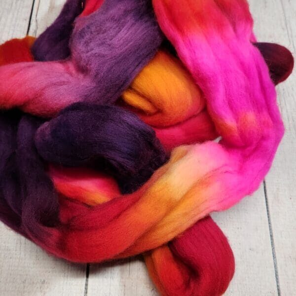 20231004_234603 A bunch of colorful roving on a wooden table.