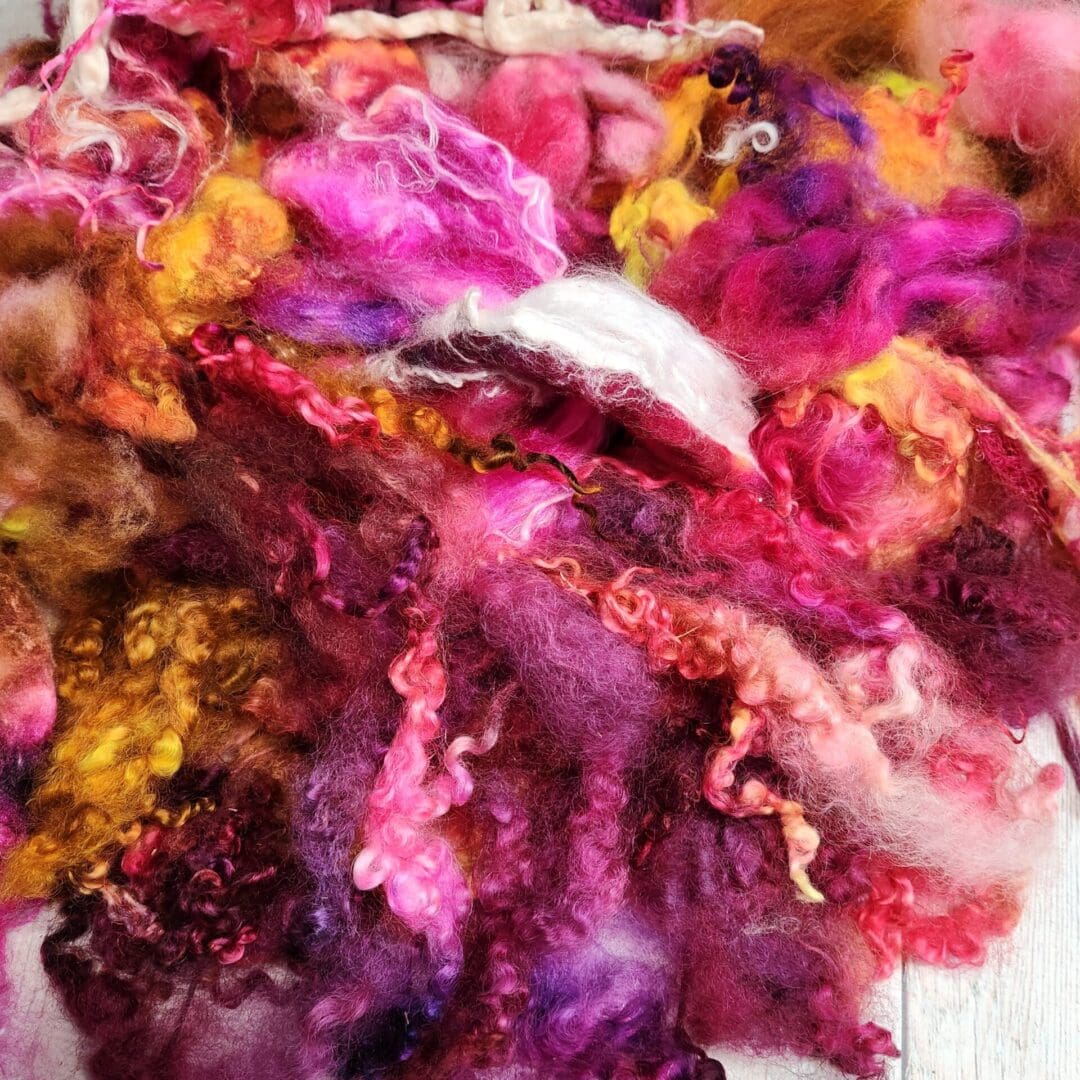 Colorful fluffy yarn in pink, yellow, and purple.